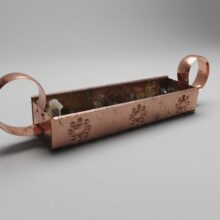 прямоугольный медный подсвечник‑контейнер с кольцевыми ручками.